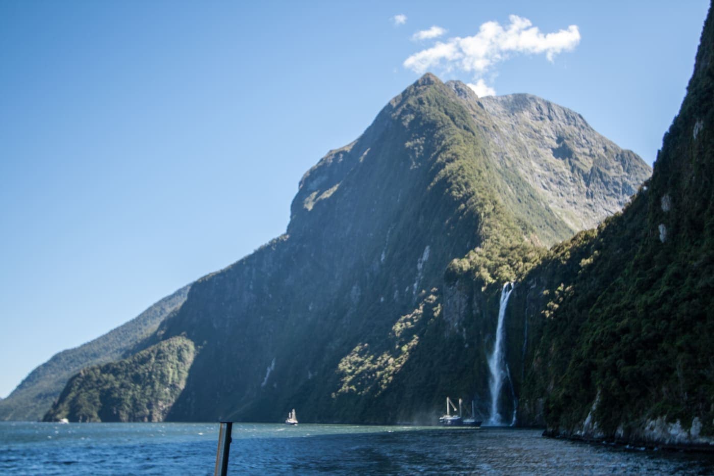 A waterfall tumbling down a steep fiord wall beside a mountain at Milford Sound